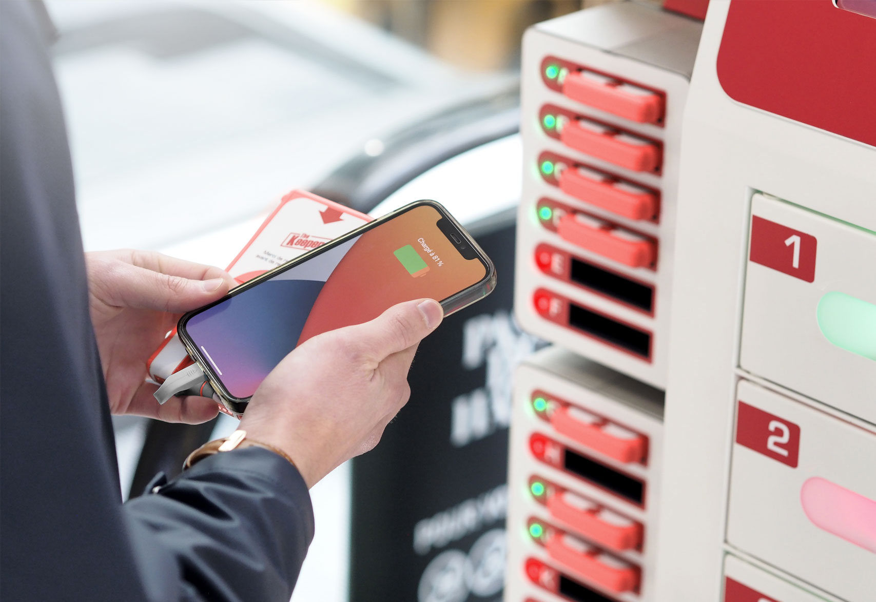 Ein Besucher hält sein Handy, das an einer Powerbank hängt, vor den Fächern eines Keeper Flash