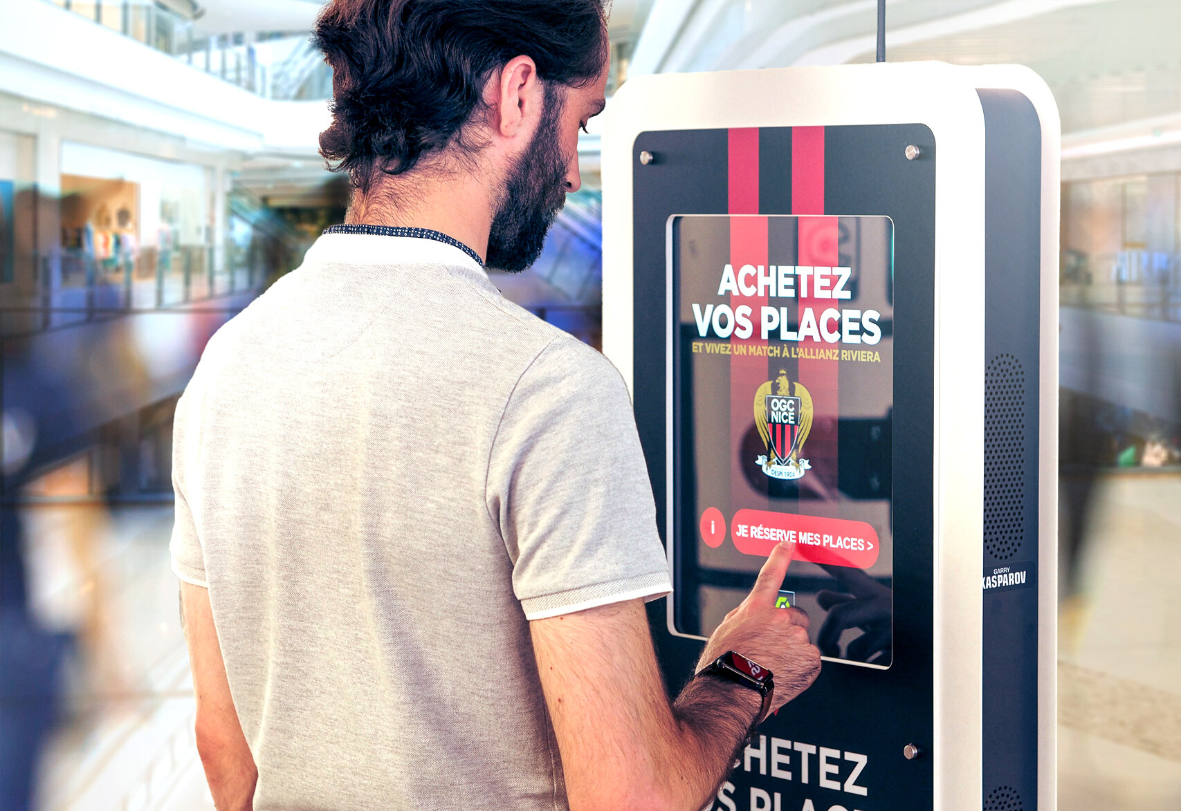 Un transeúnte compra una entrada para un partido en una Ticket Station con los colores del OGC Nice
