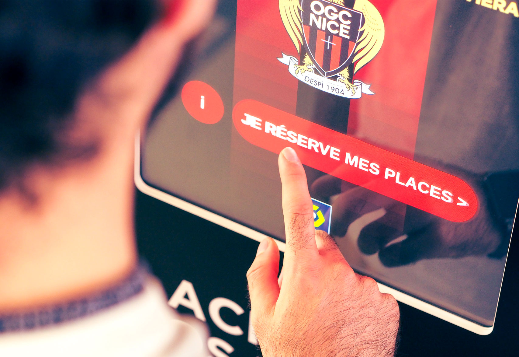 Un dito preme «Je réserve mes places» (Prenoto i miei posti) sullo schermo di una Ticket Station dell'OGC Nice