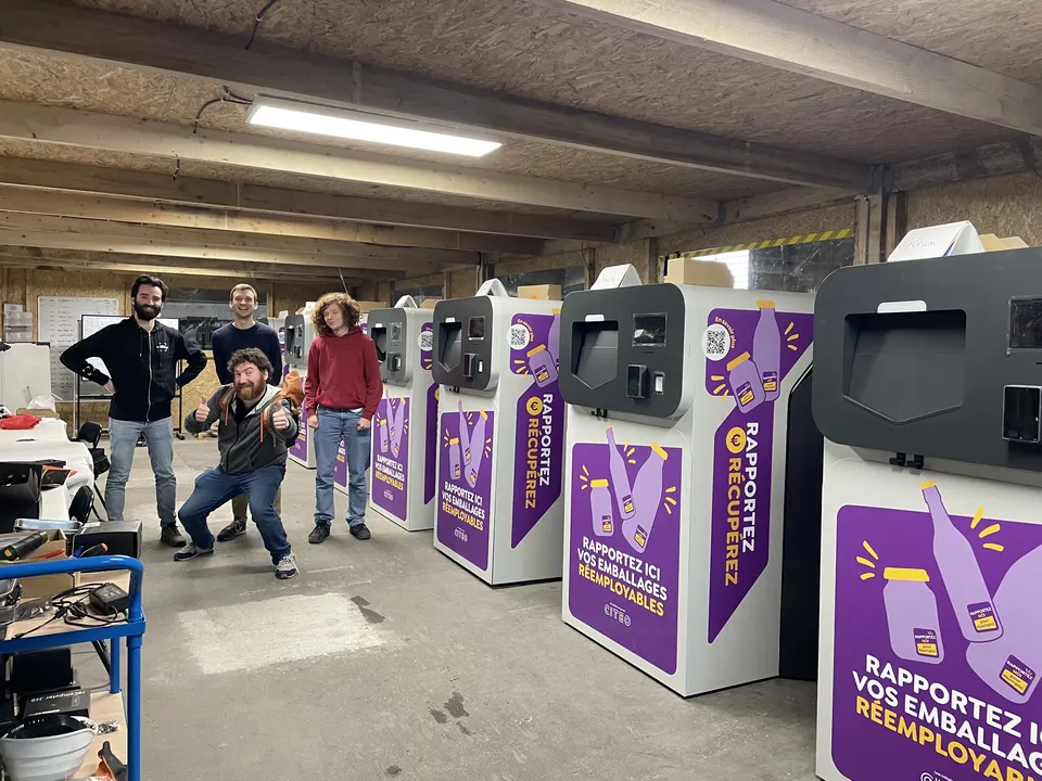Trois membres de l'équipe posent, l'un le pouce levé, à côté d'une rangée de Collectors prêts à partir