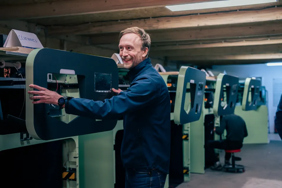 Un membre de l'équipe, tout sourire, au montage d'une rangée de Collectors à l'atelier