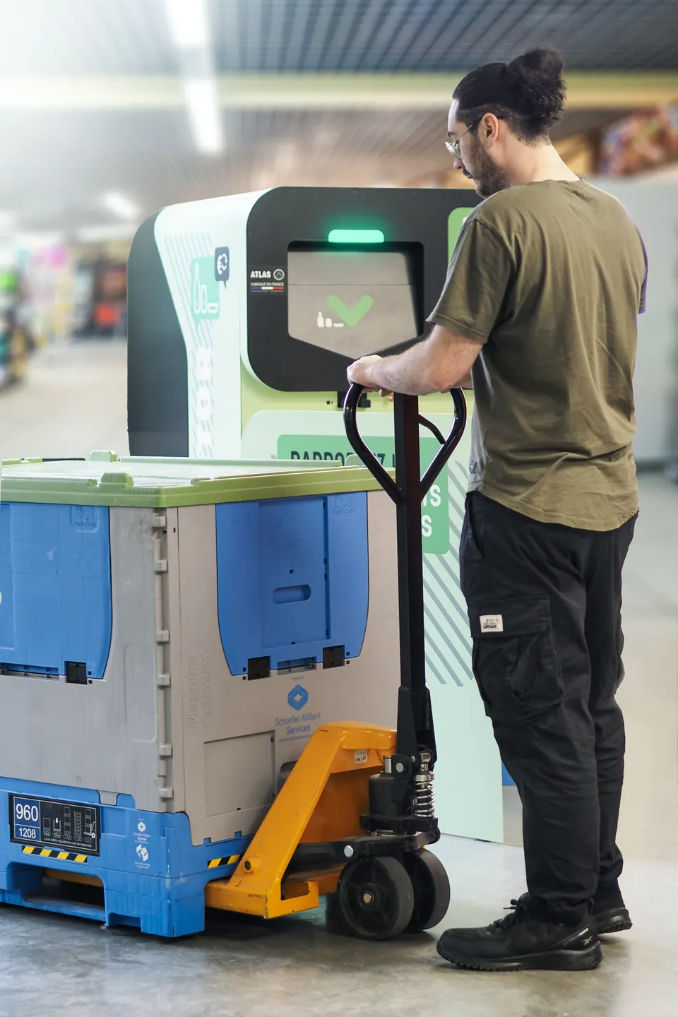 A store employee swaps the Collector's full pallet box using a manual pallet truck